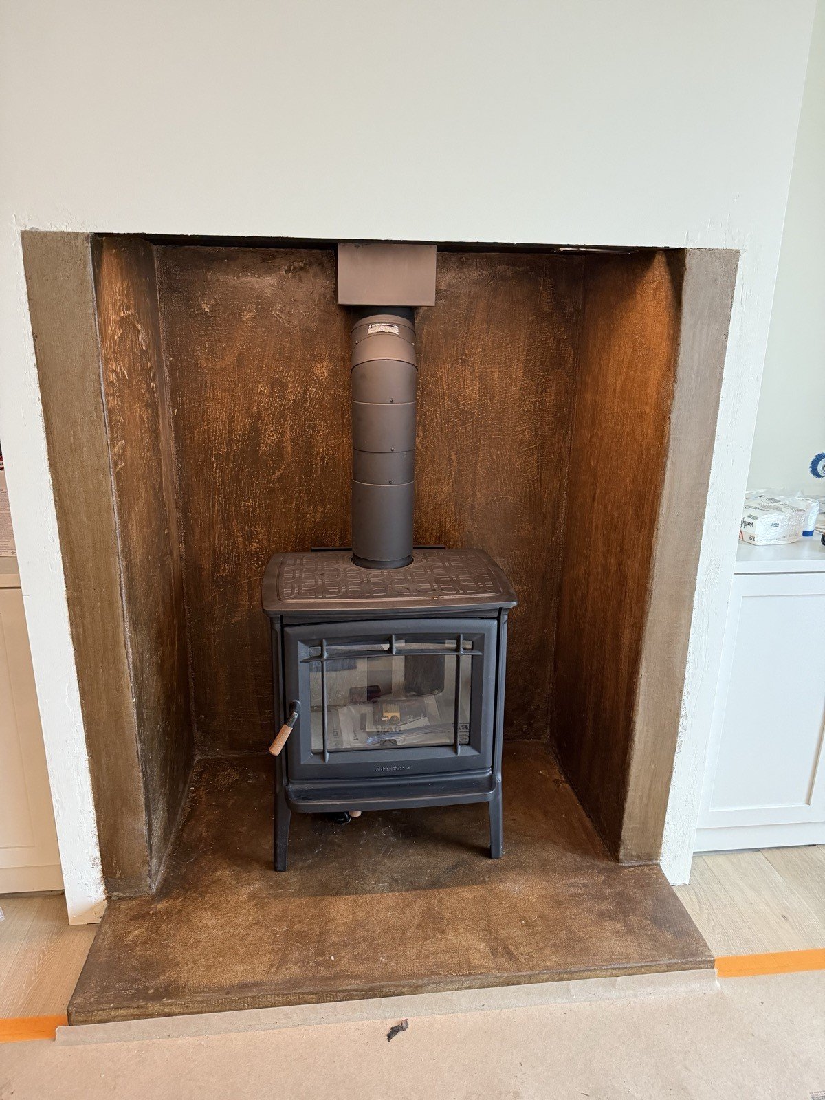 Wood stove installed in a custom-finished fireplace niche